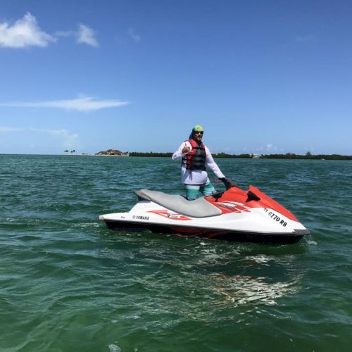 A person relaxing on a jet ski on blue water under a clear sky, sunny day.